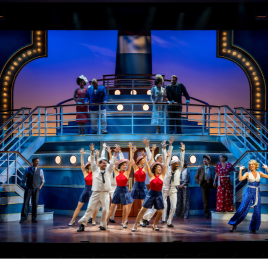 A full cast dressed in 1930 sailing attire, dancing